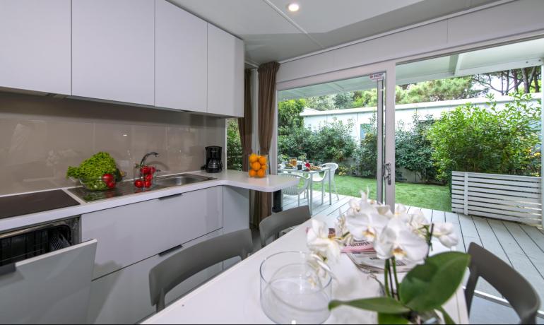 Cucina moderna luminosa con vista su giardino verde e fiori.