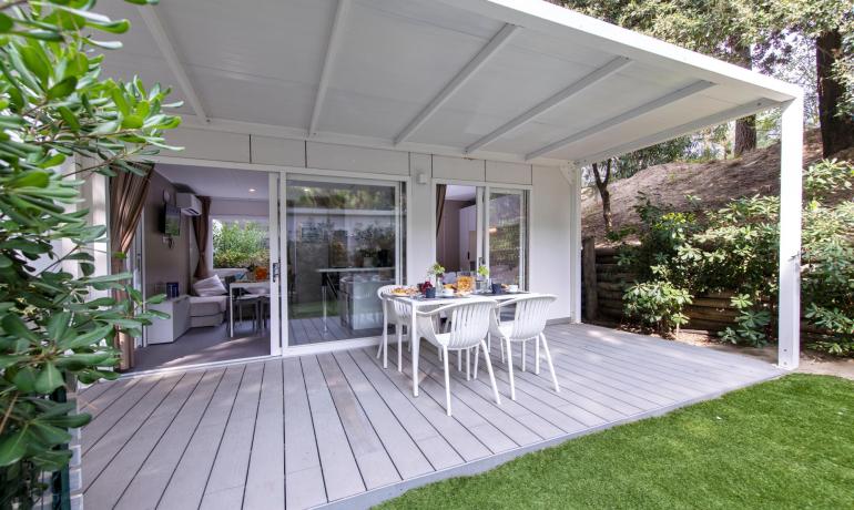 Veranda accogliente con tavolo apparecchiato, immersa nel verde.