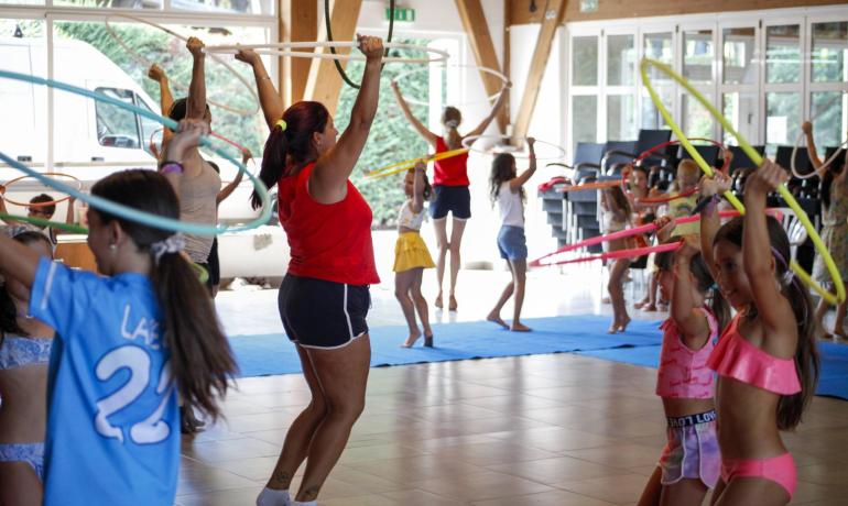 Kinder und Erwachsene spielen mit Hula-Hoop-Reifen in einer lebhaften und fröhlichen Umgebung.