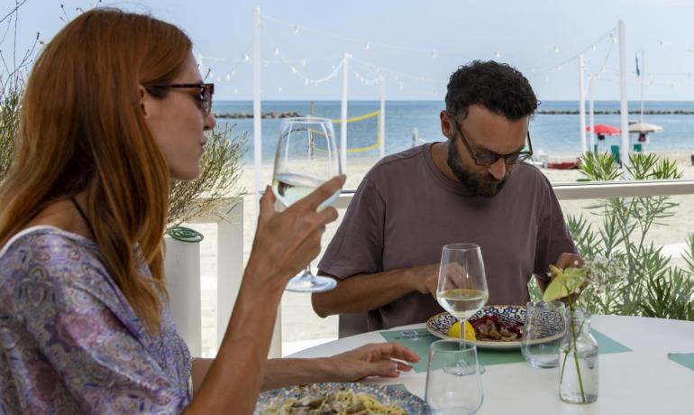 Famiglia felice pranza in riva al mare, sole e relax.