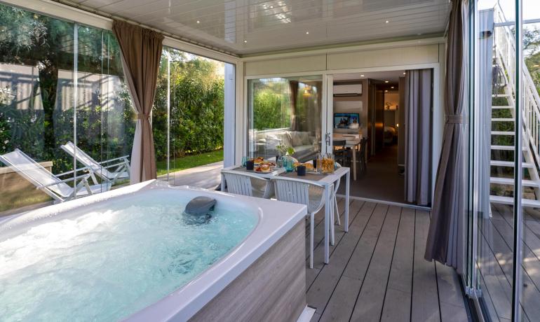 Veranda con jacuzzi, tavolo apparecchiato, ambiente rilassante e luminoso.