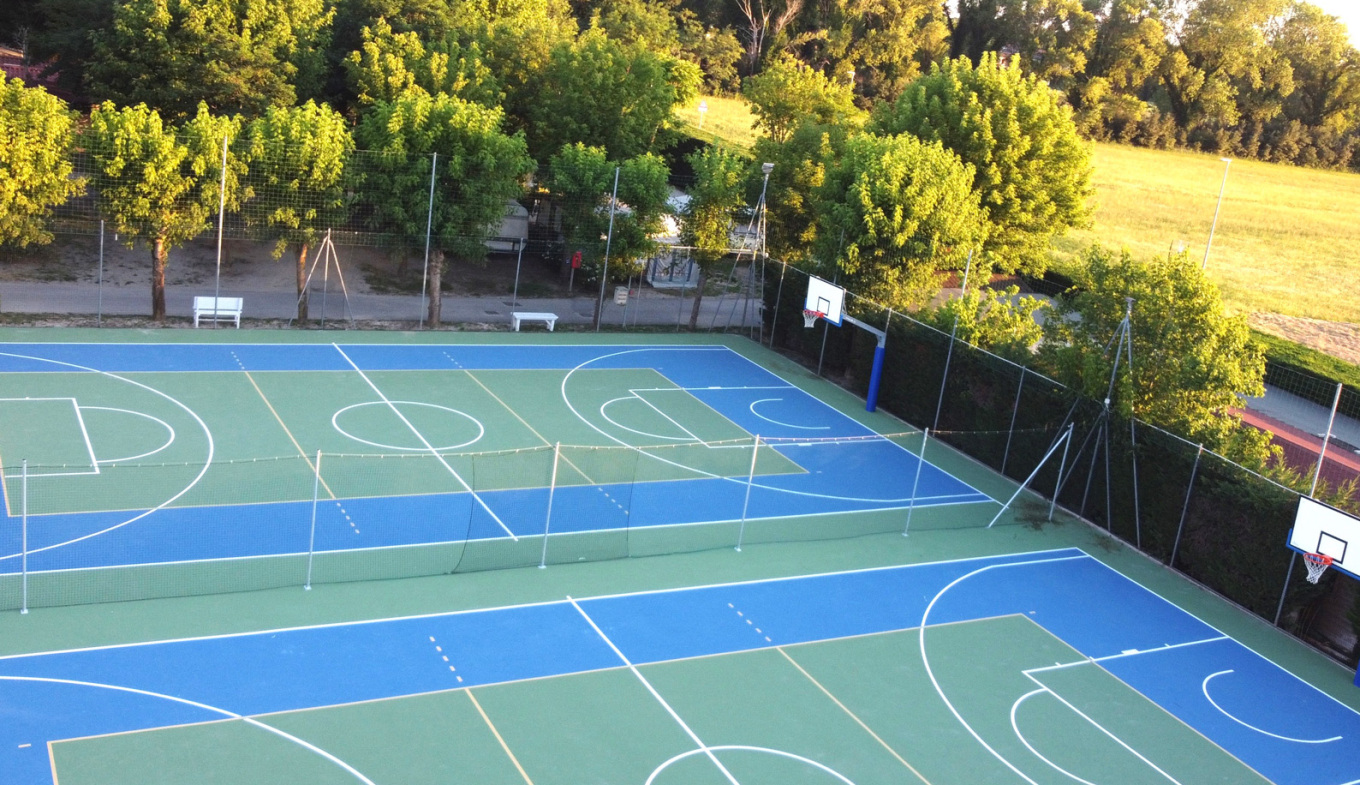 Campi sportivi immersi nel verde, evocano libertà e vitalità sotto il sole estivo.