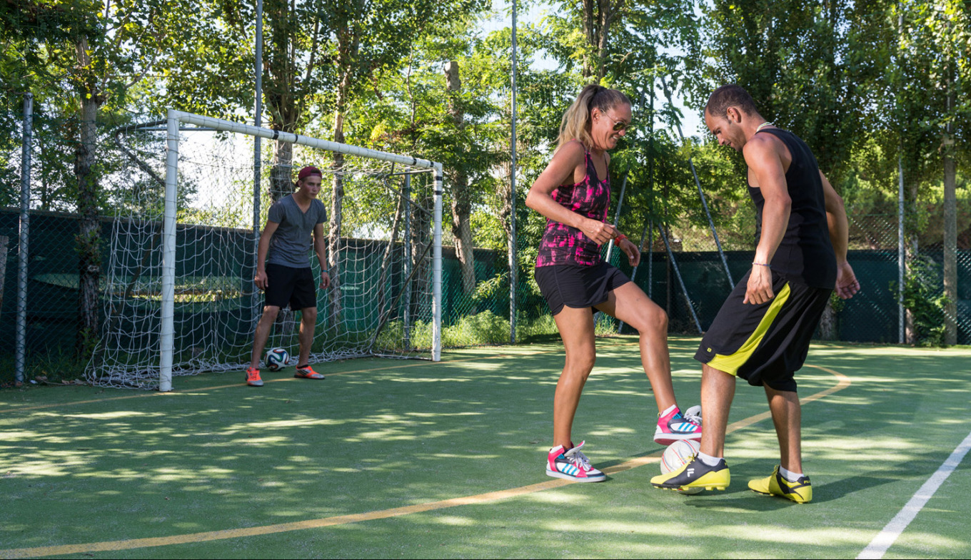 Due persone giocano a calcio con allegria, mentre un portiere osserva attento.