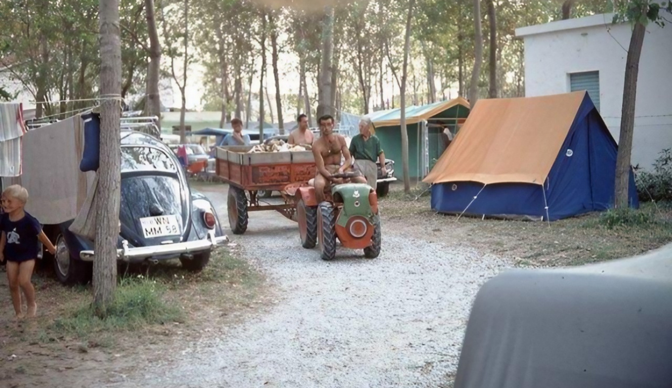 Campeggio estivo: risate, un trattore, tende colorate, un bambino felice e natura rigogliosa.