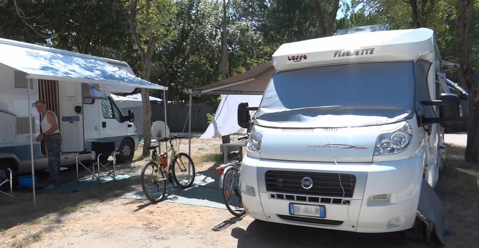 Camper estivi, biciclette, ombra di alberi, atmosfera rilassata di campeggio all'aperto.