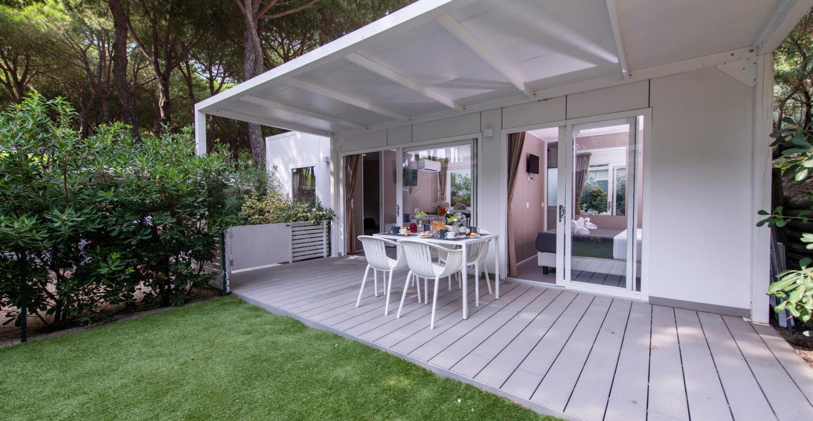 Terrazza moderna, immersa nel verde, con tavolo apparecchiato per un pasto all'aperto.