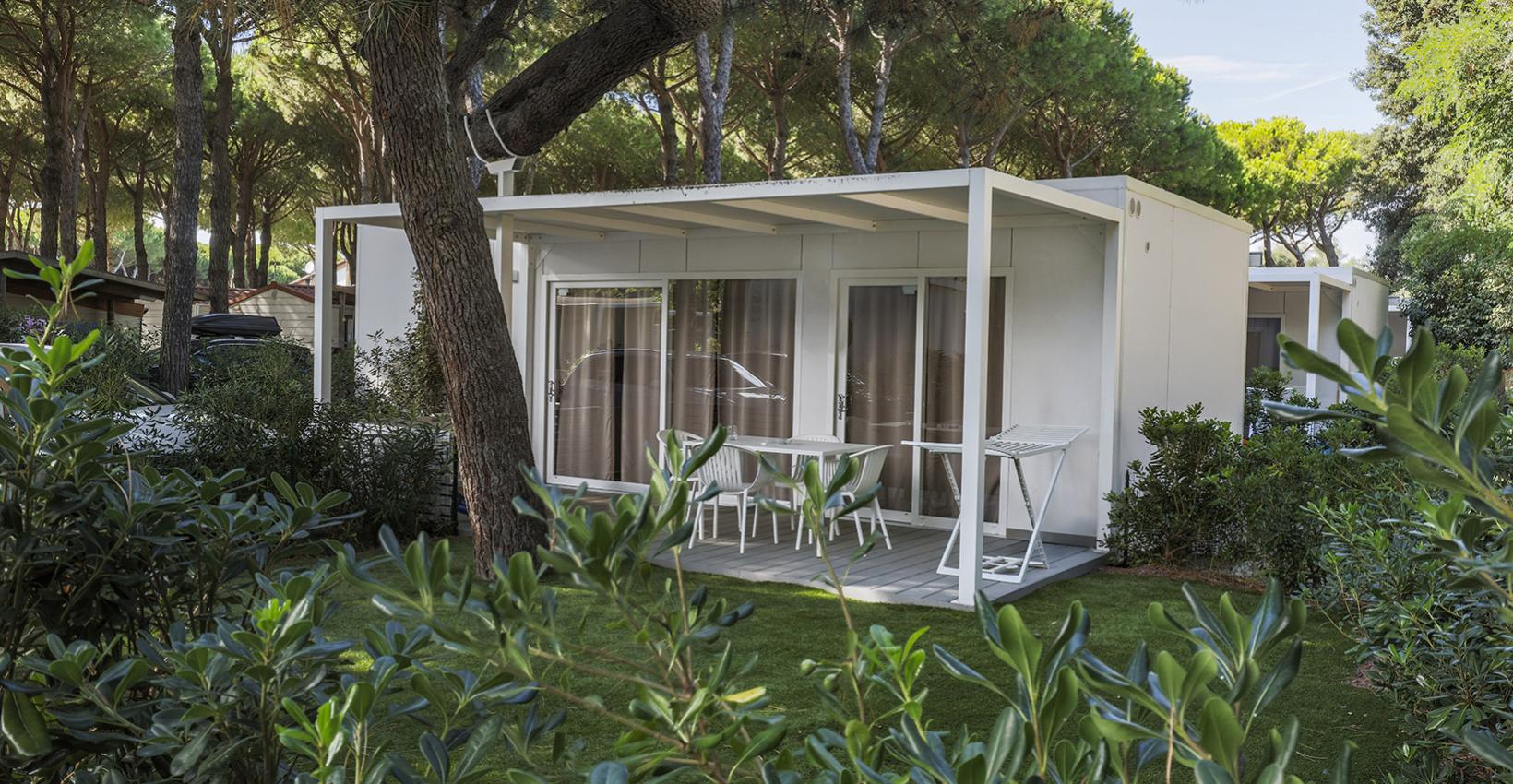 Bungalow moderno immerso nel verde, tra pini alti e atmosfera serena e rilassante.