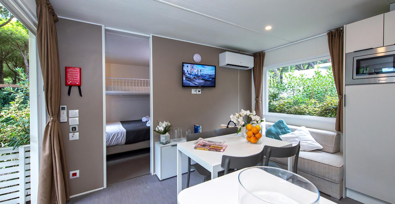 Interno moderno e luminoso, con tavolo bianco, divano beige, fiori e arance su tavolo.