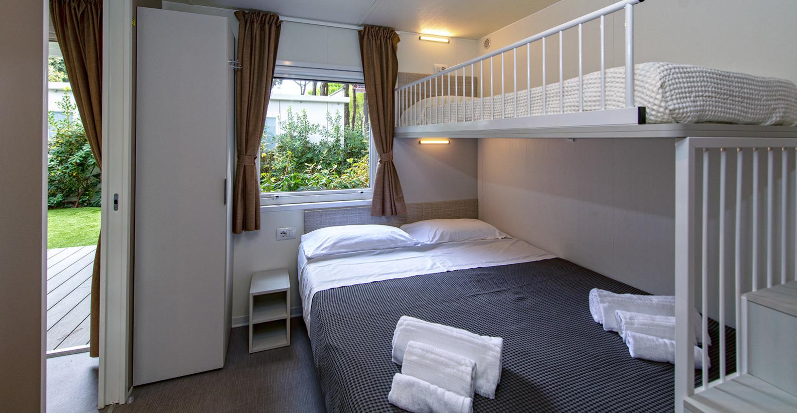 Camera accogliente con letto a castello, lenzuola fresche e vista su giardino verde.