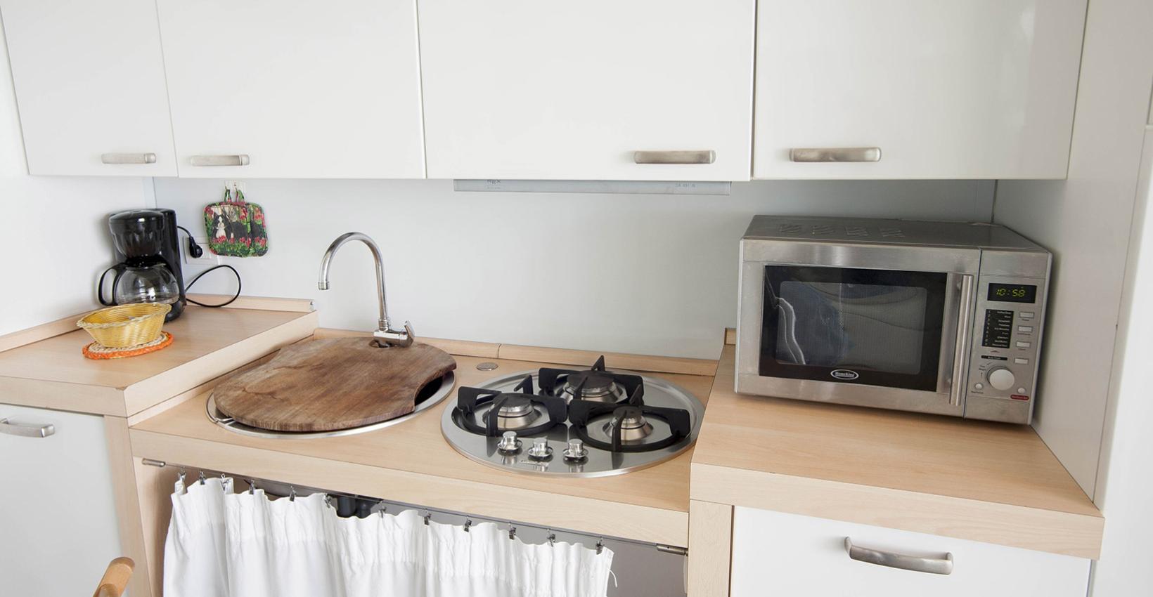 Cucina moderna e luminosa con microonde, fornelli e caffettiera, atmosfera ordinata e accogliente.