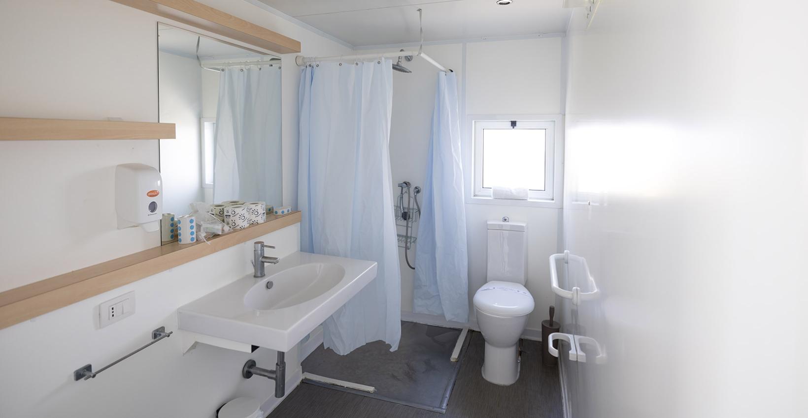 Bagno moderno e luminoso, con doccia, lavandino e servizi igienici, atmosfera pulita e ordinata.