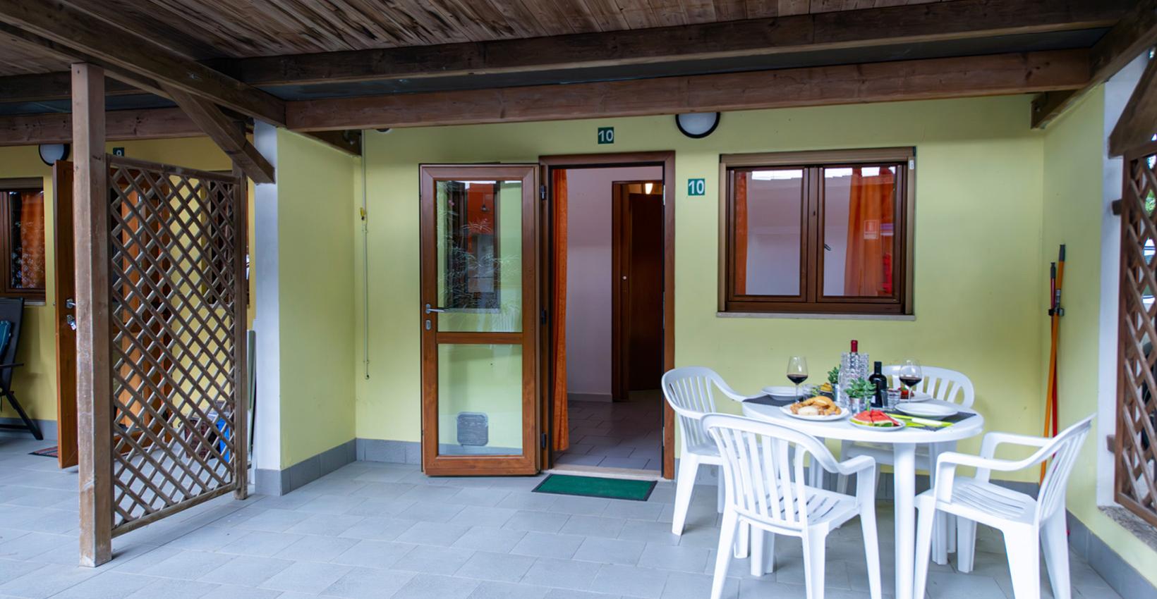 Terrazza accogliente, tavolo apparecchiato con vino e cibo, atmosfera rilassante e conviviale.