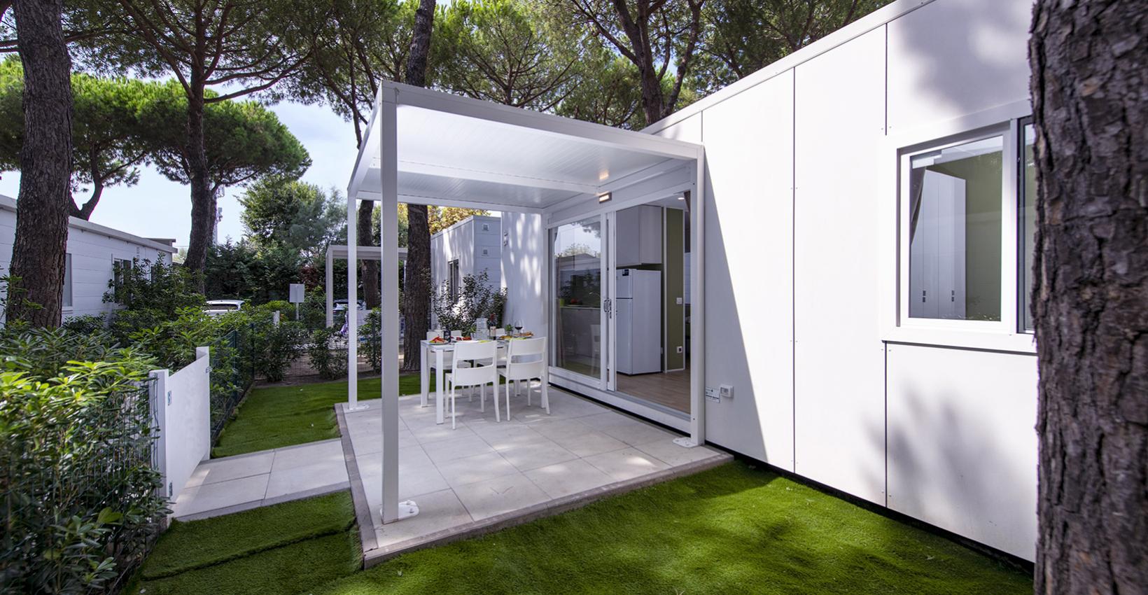 Terrazza moderna nel verde, con tavolo apparecchiato, circondata da pini maestosi.