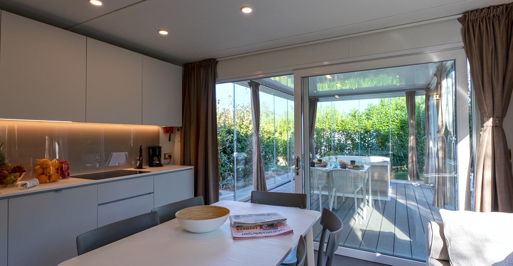 Cucina moderna luminosa, vista su veranda verde, atmosfera accogliente e rilassante.
