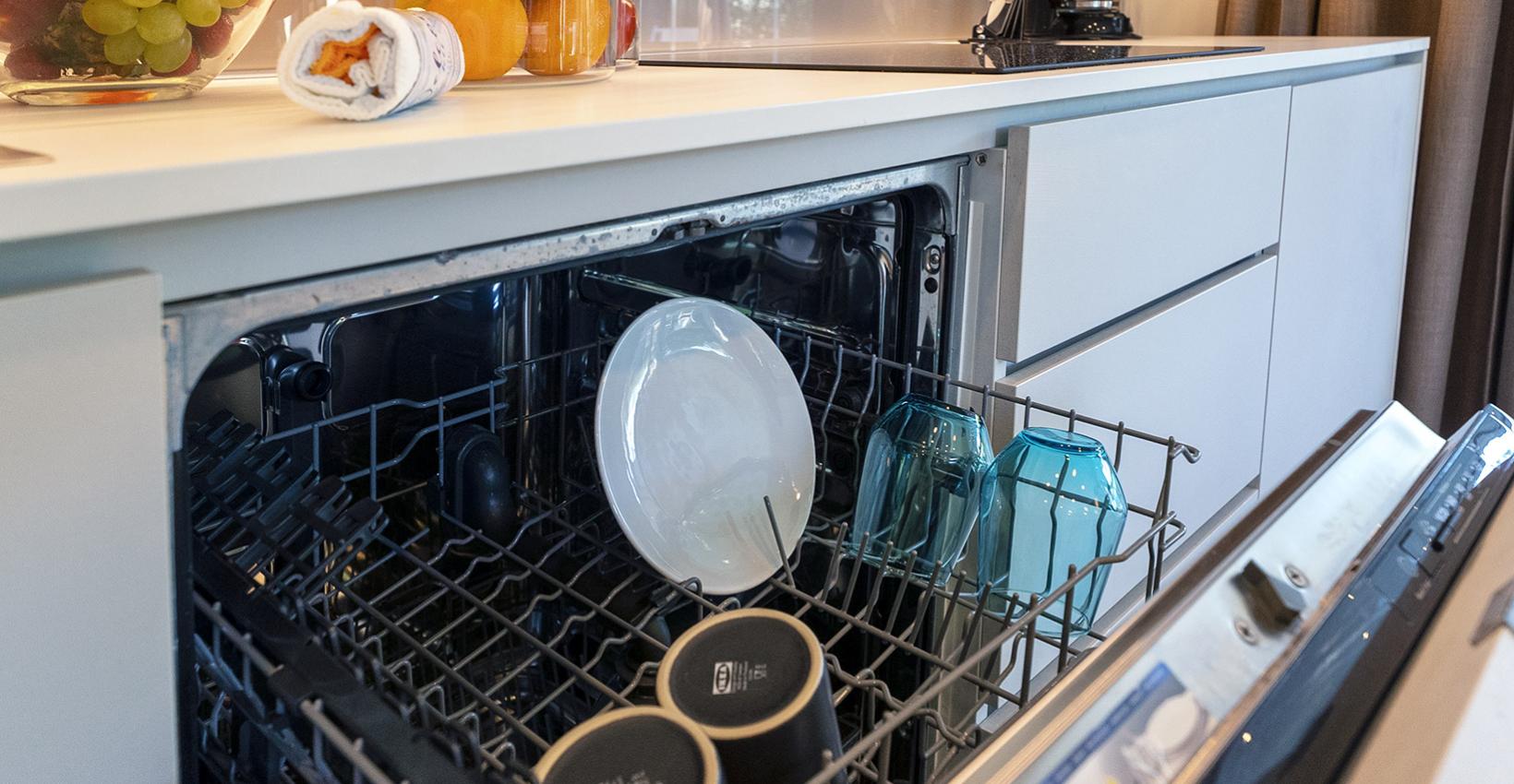 Cucina moderna con lavastoviglie aperta, frutta fresca e atmosfera accogliente.