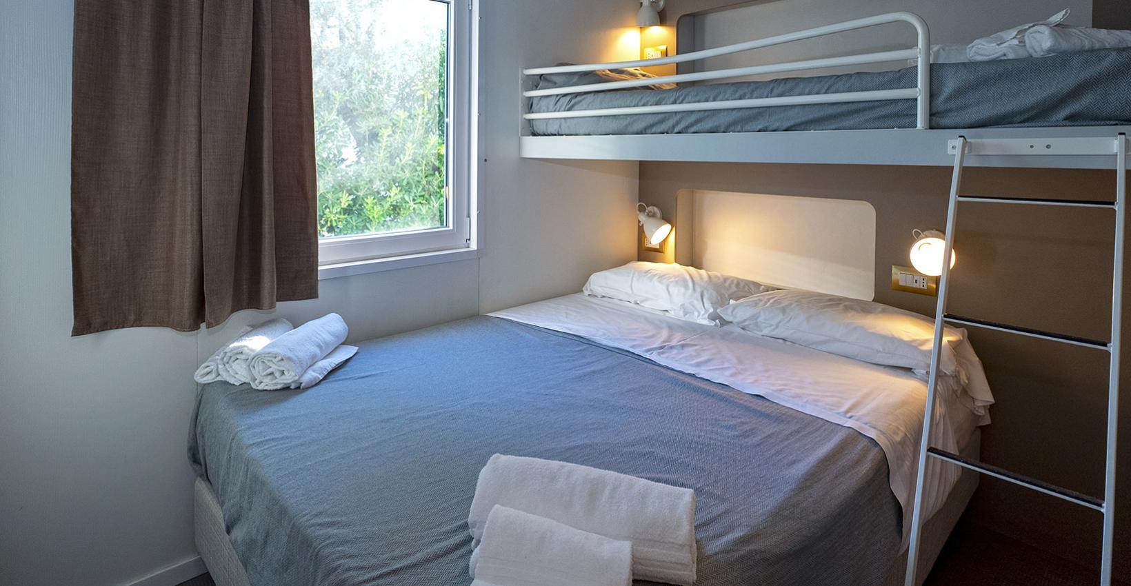 Camera accogliente con letto matrimoniale e letto a castello, illuminata da luci calde.