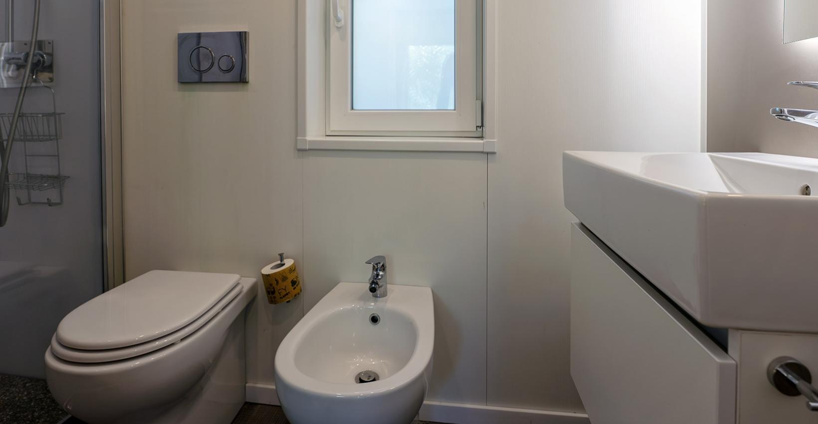 Bagno moderno e luminoso con sanitari eleganti, finestra aperta e ambiente sereno.