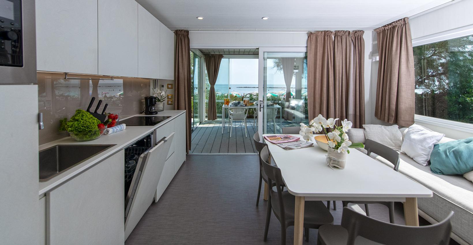 Cucina moderna luminosa con vista mare, tavolo accogliente e atmosfera rilassante.