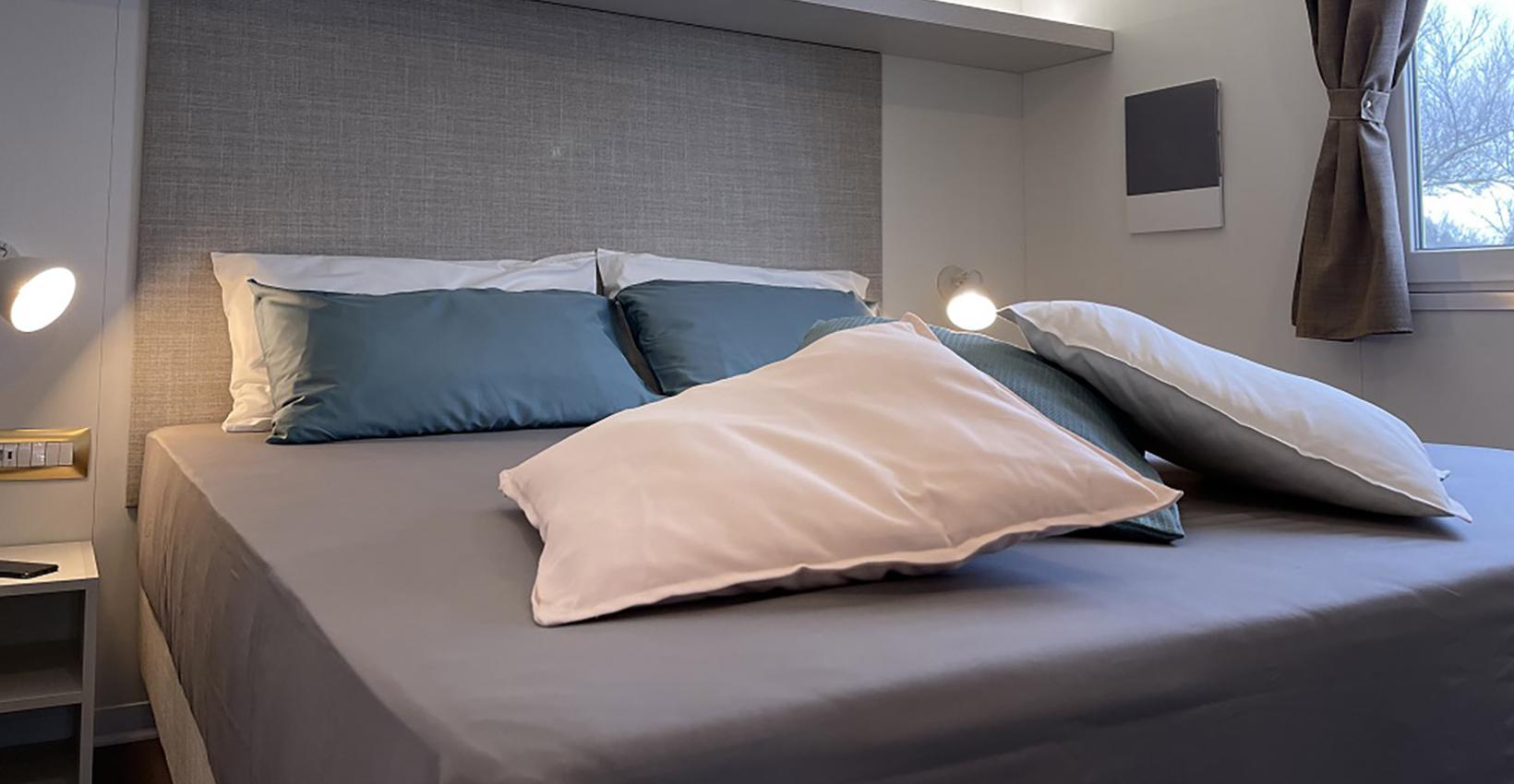 Camera accogliente con letto elegante, cuscini soffici e luce calda, atmosfera rilassante e serena.