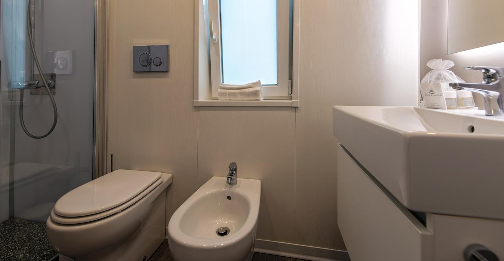 Bagno moderno, pulito e luminoso con doccia, bidet e finestra accogliente.