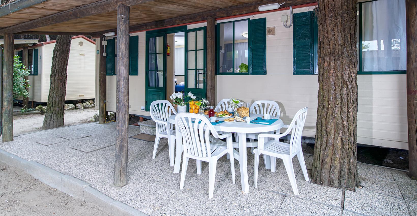 Bungalow immerso nella natura, veranda accogliente con tavolo apparecchiato per una colazione all'aperto.