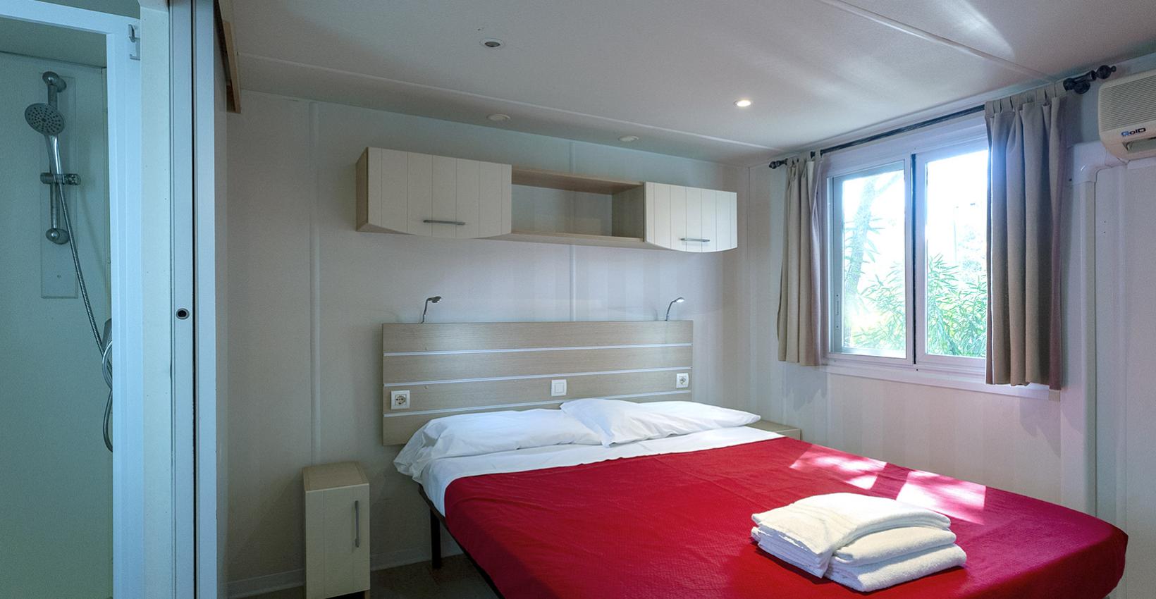 Camera luminosa con letto matrimoniale, copriletto rosso e bagno privato, accogliente e moderna.