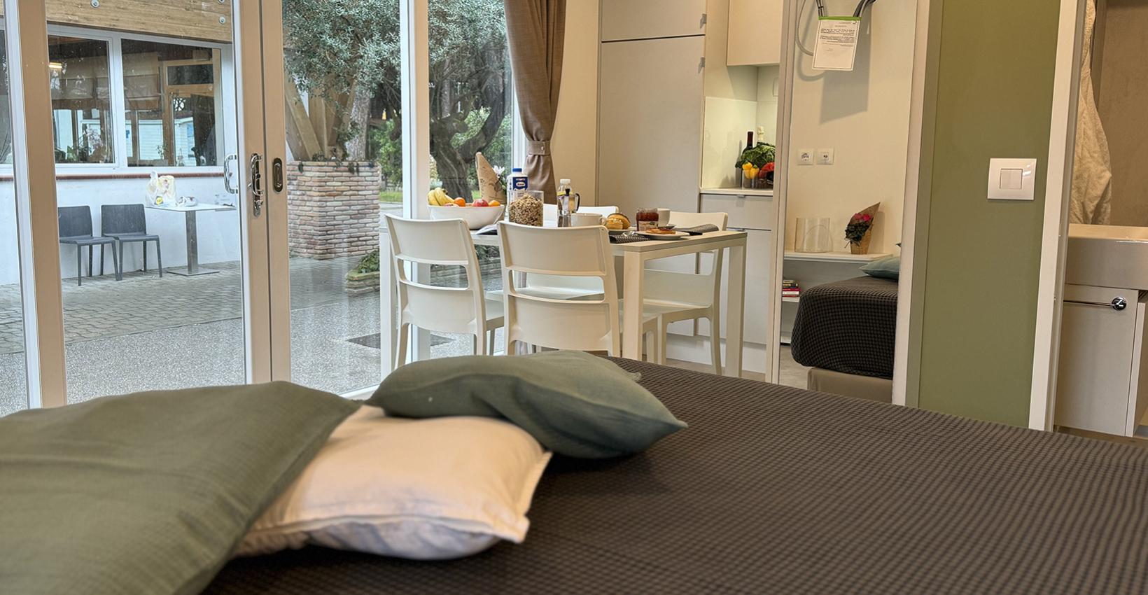 Accogliente monolocale con vista giardino, tavolo apparecchiato e atmosfera calda e rilassante.