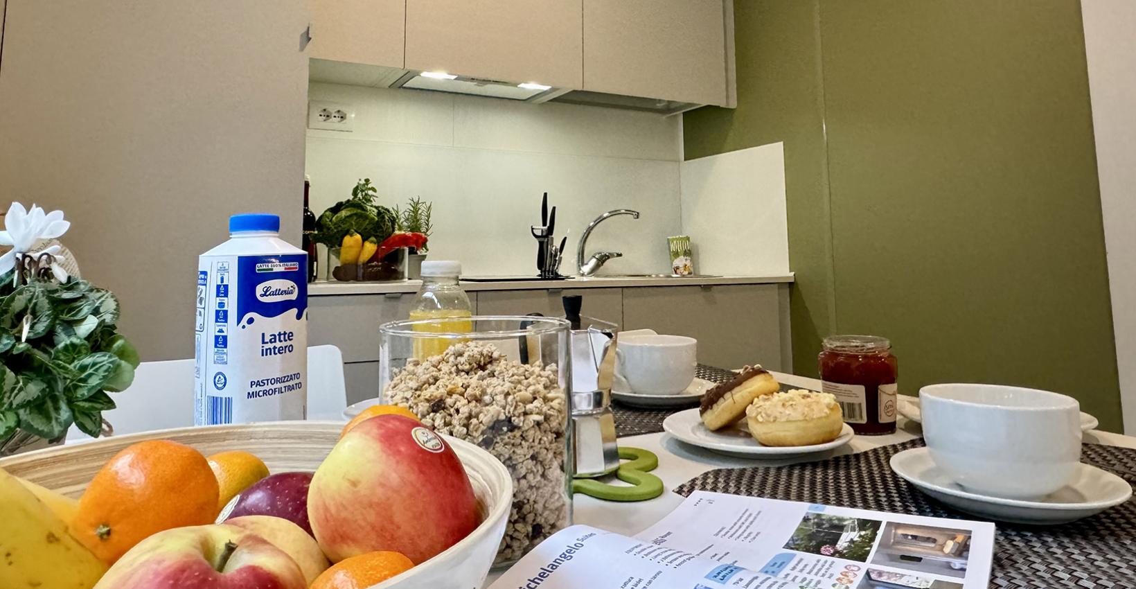 Colazione casalinga: frutta, dolci, caffè e latte in una cucina accogliente e luminosa.