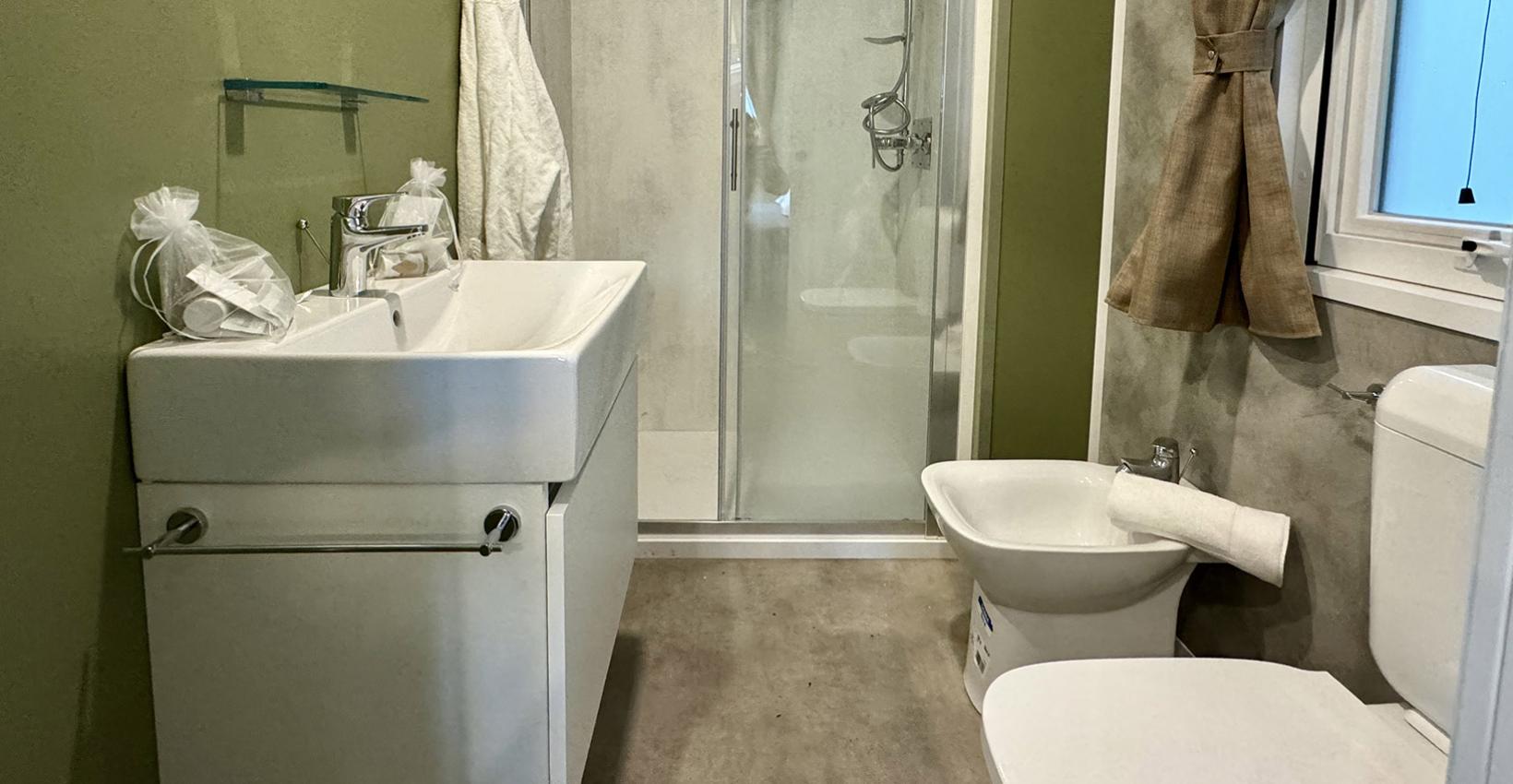 Bagno moderno e ordinato, colori tenui, atmosfera rilassante con doccia elegante e accessori curati.
