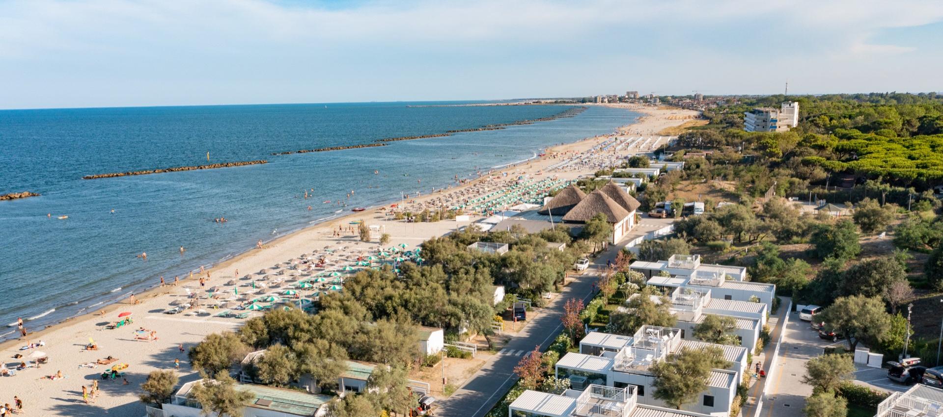 Spiaggia soleggiata, mare calmo, ombrelloni colorati, atmosfera estiva rilassante e gioiosa.