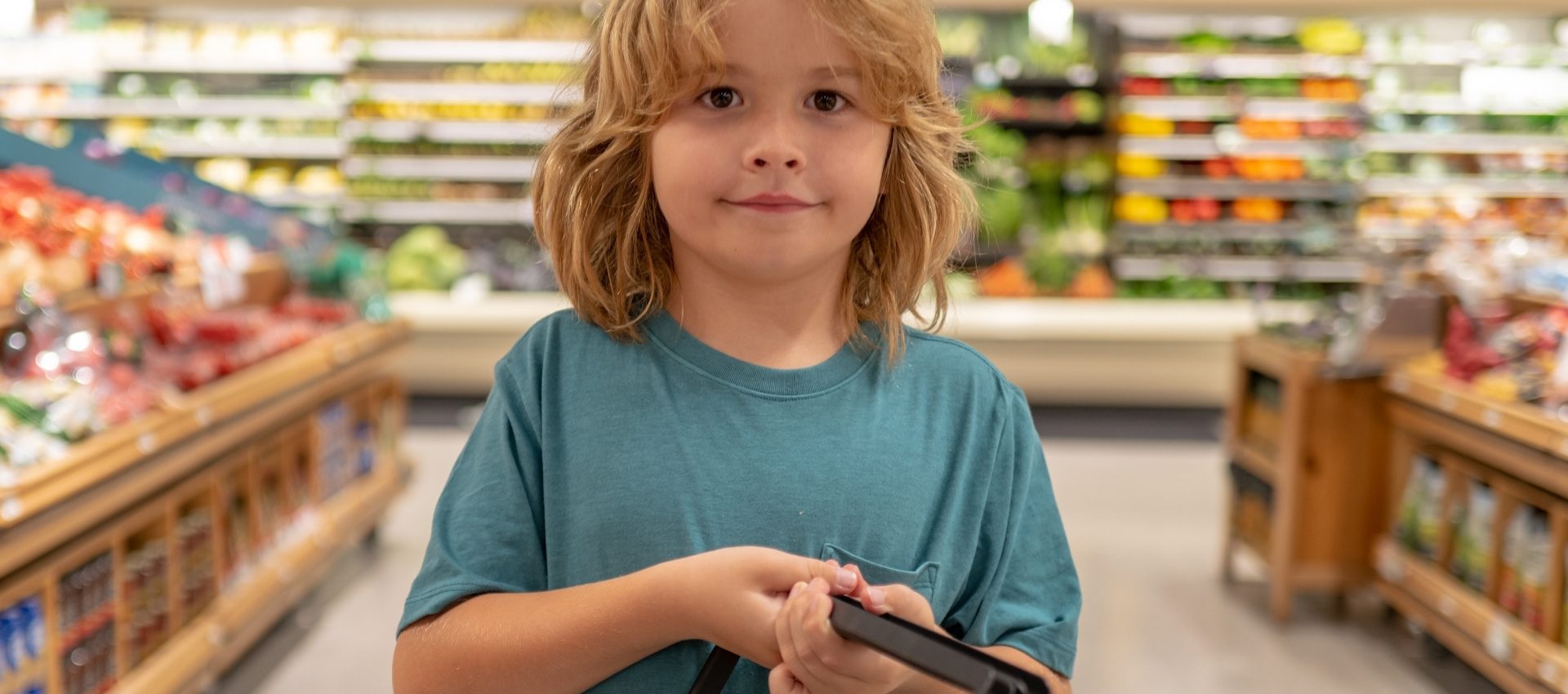 Bambino sorridente in supermercato, atmosfera vivace e colorata, senso di curiosità e scoperta.