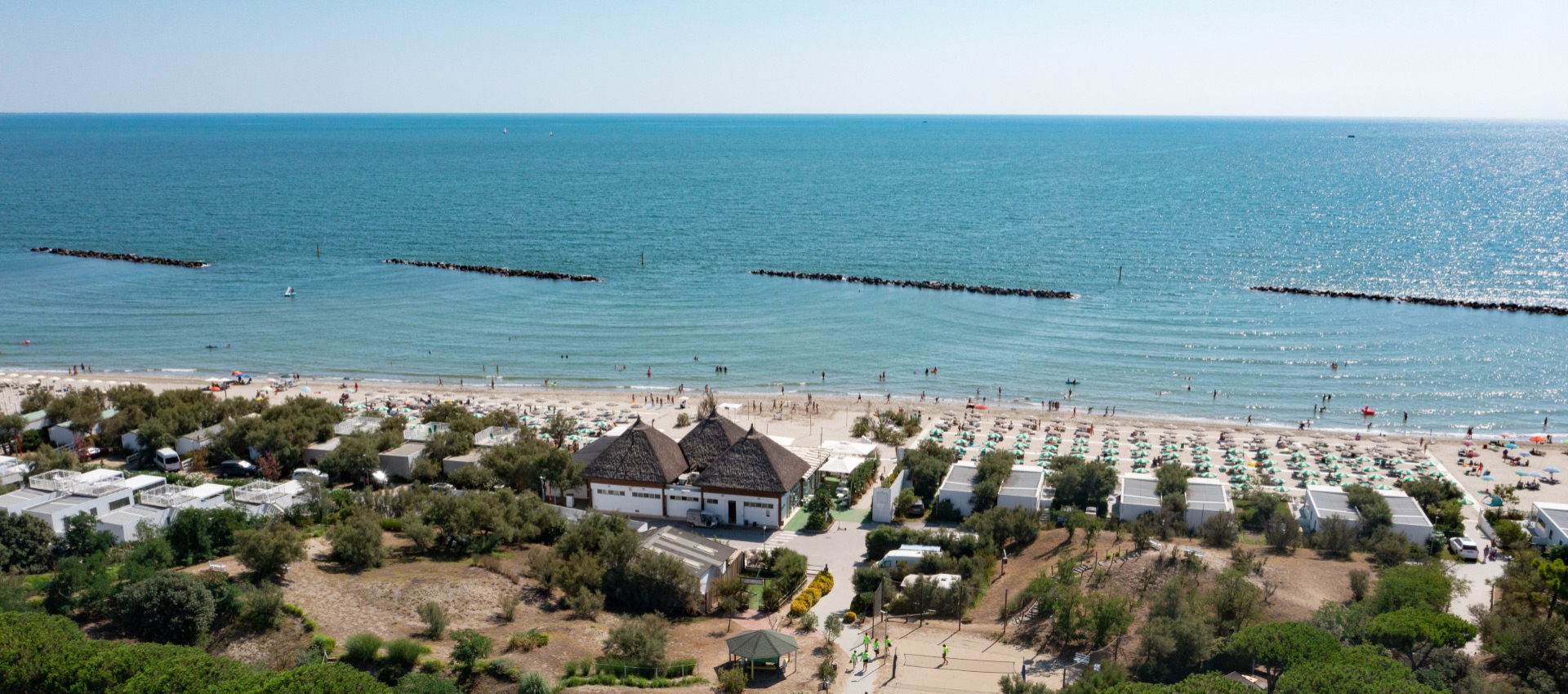 Spiaggia soleggiata, mare calmo, ombrelloni colorati, atmosfera rilassante e vacanziera.