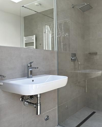 Bagno moderno e luminoso con doccia a pioggia e lavabo elegante, minimalista e rilassante.
