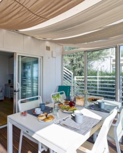 Terrazza luminosa con tavola apparecchiata, colazione invitante, vista su giardino, atmosfera rilassante.