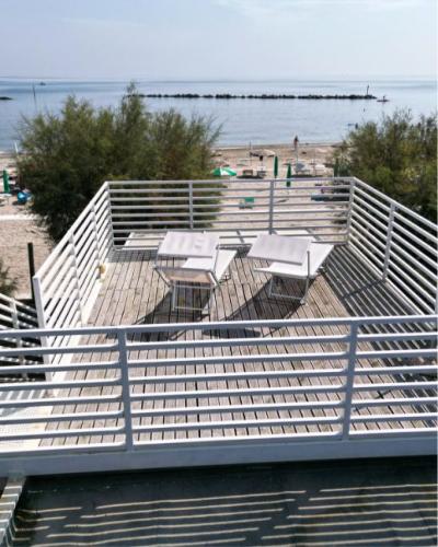 Terrazza sul mare, due lettini bianchi, sole e pace sulla spiaggia.
