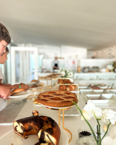 Buffet di dolci con crostate, torte e croissant in un ambiente luminoso e accogliente.