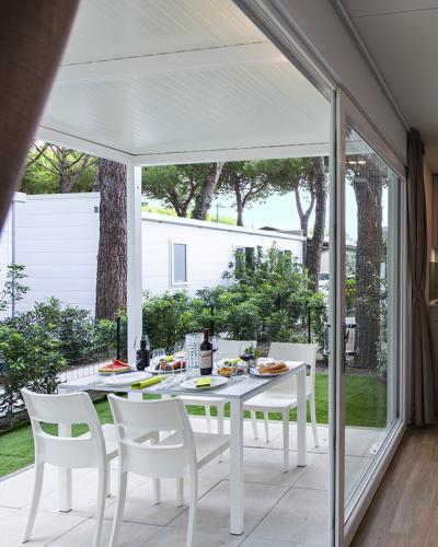 Interno luminoso, cucina moderna, tavolo apparecchiato, vista su giardino verde e alberi.