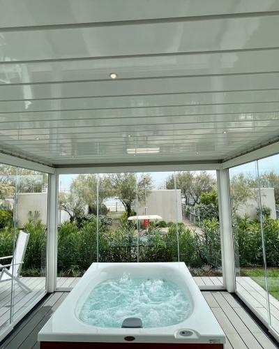 Vasca idromassaggio in veranda luminosa, immersa nel verde, crea un'atmosfera rilassante e serena.