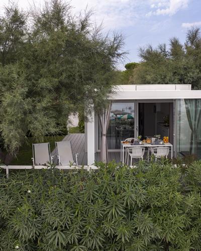 Bungalow immerso nel verde, tavolo apparecchiato per colazione, atmosfera rilassante e naturale.