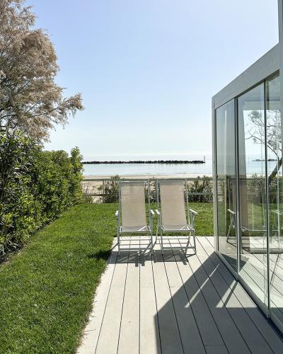 Due sedie su terrazza soleggiata, vista mare, atmosfera tranquilla e rilassante.