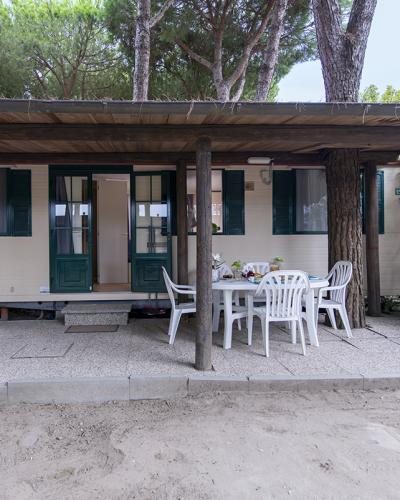Bungalow tra gli alberi, veranda accogliente con tavolo e sedie, atmosfera di vacanza rilassante.