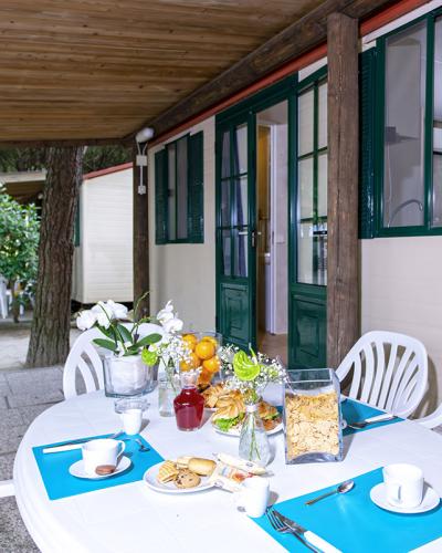 Colazione all'aperto luminosa e invitante su un tavolo bianco, circondato da verde.