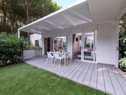 Terrazza moderna, immersa nel verde, con tavolo apparecchiato per un pasto all'aperto.