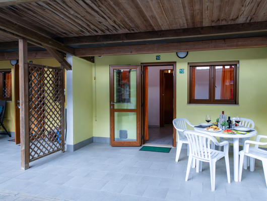 Terrazza accogliente, tavolo apparecchiato con vino e cibo, atmosfera rilassante e conviviale.