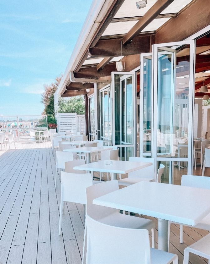 Terrazza luminosa sul mare, sedie bianche, atmosfera rilassante e serena.