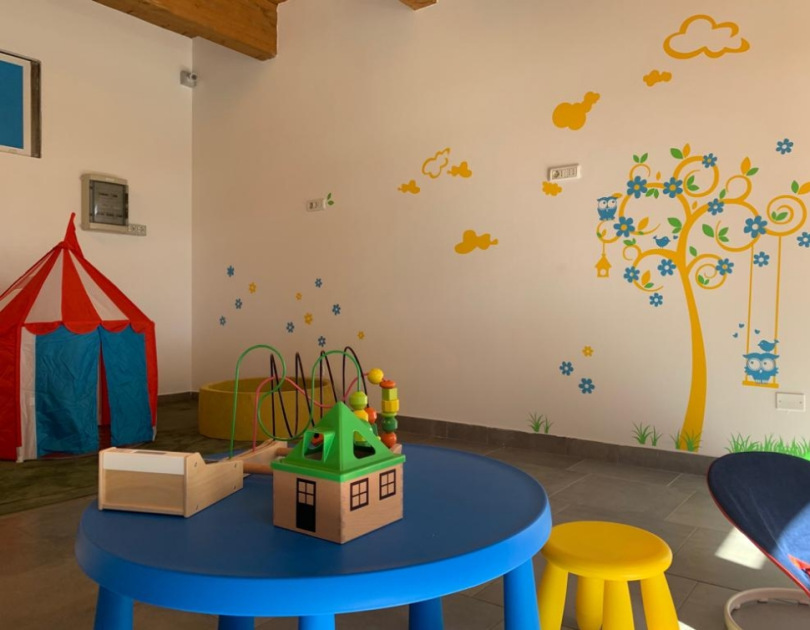 Stanza colorata per bambini con giochi, tenda rossa e murale allegro.
